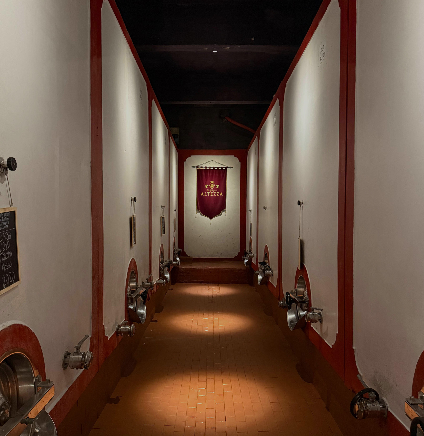 The concrete fermentation vats of Altezza Winery lining a lit corridor, the estate banner hanging at the end