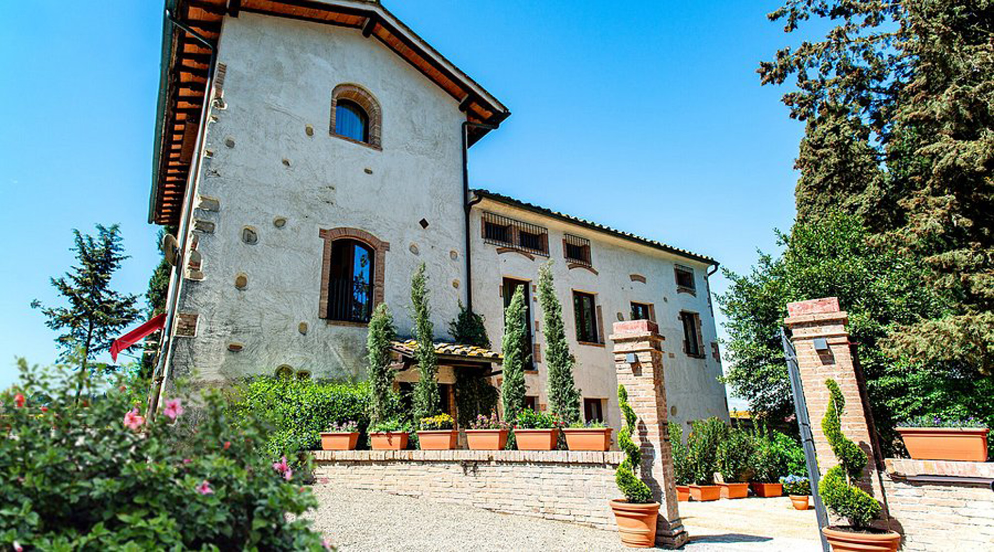 Esterno di Hotel Torciano Vecchio Asilo, edificio di campagna restaurato con cipressi e vasi in terracotta