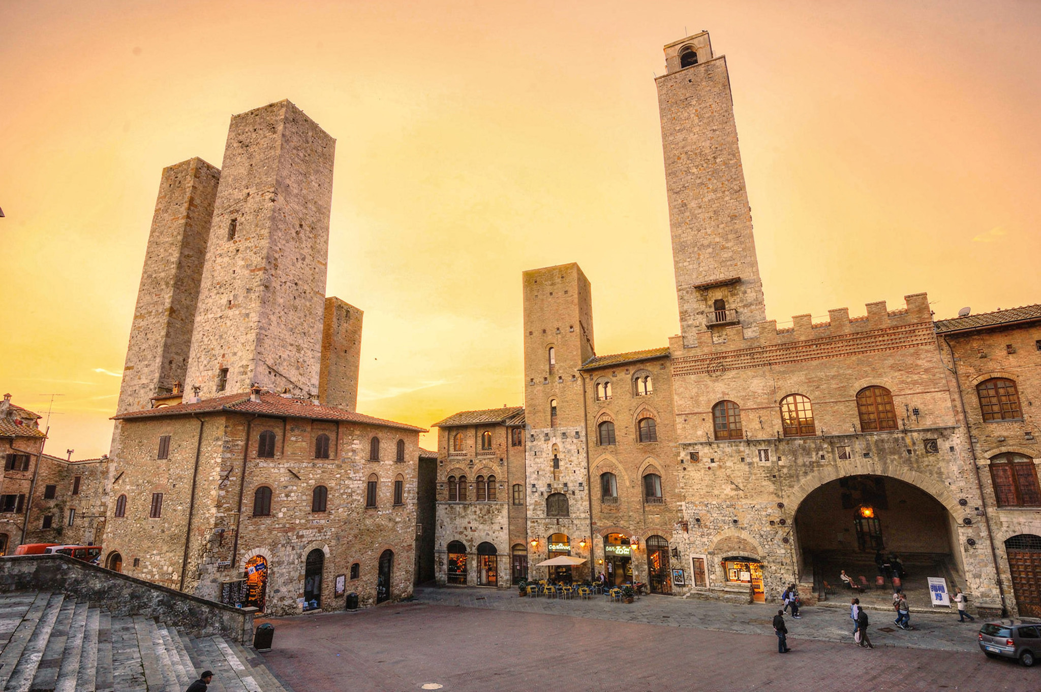 La piazza principale di San Gimignano nell'ora dorata, circondata da case torri in pietra