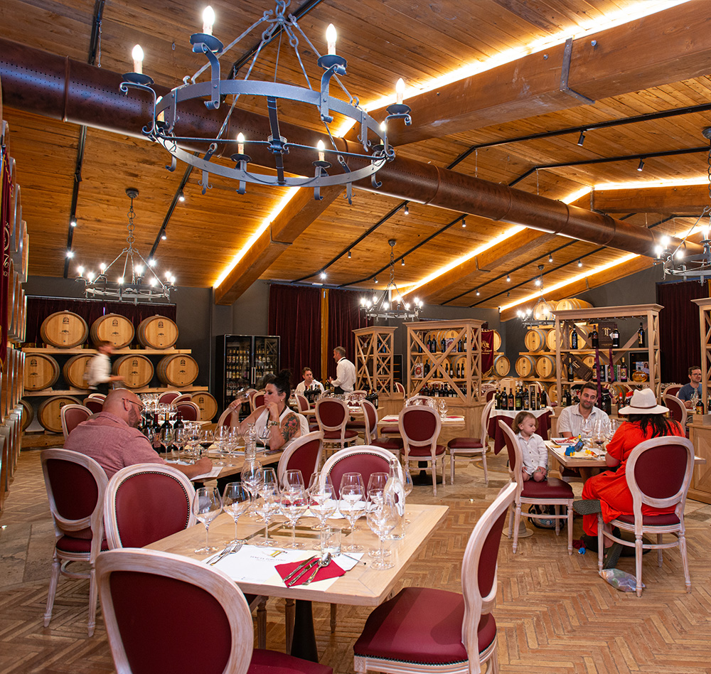 Ospiti a pranzo nella sala delle barrique di Tenuta Torciano, tavoli apparecchiati con calici