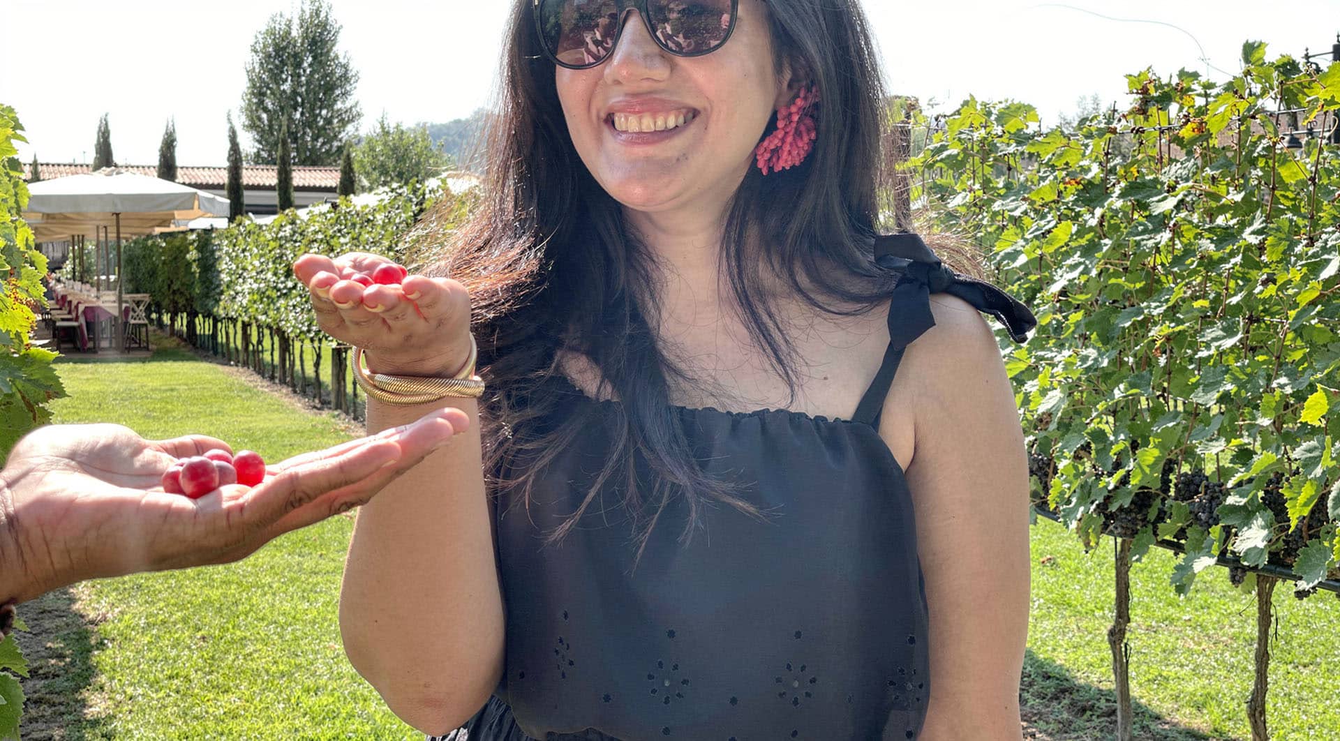 A guest smiling as she holds a bunch of grapes