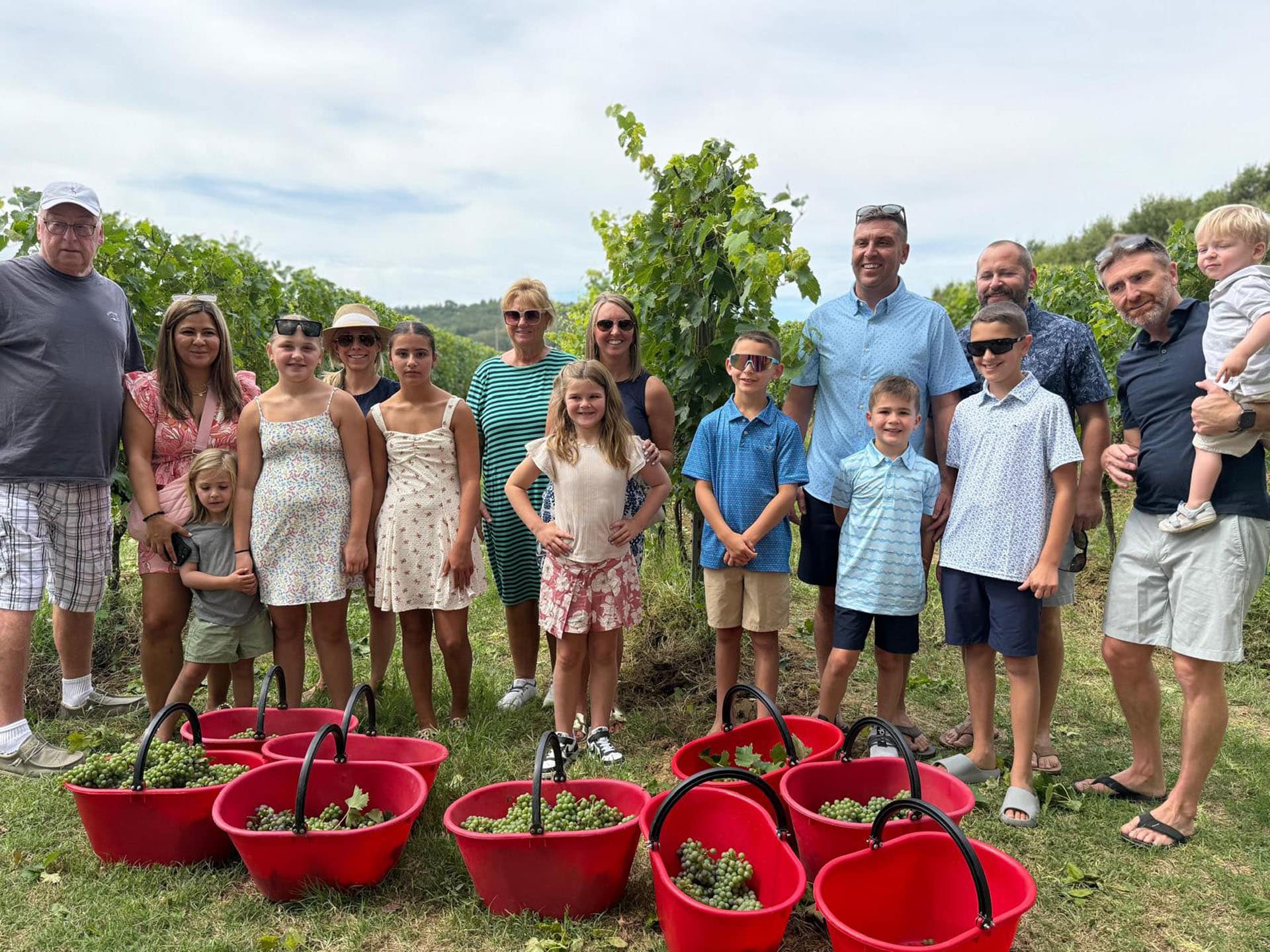 A family group in the vineyard behind a row of red harvest baskets