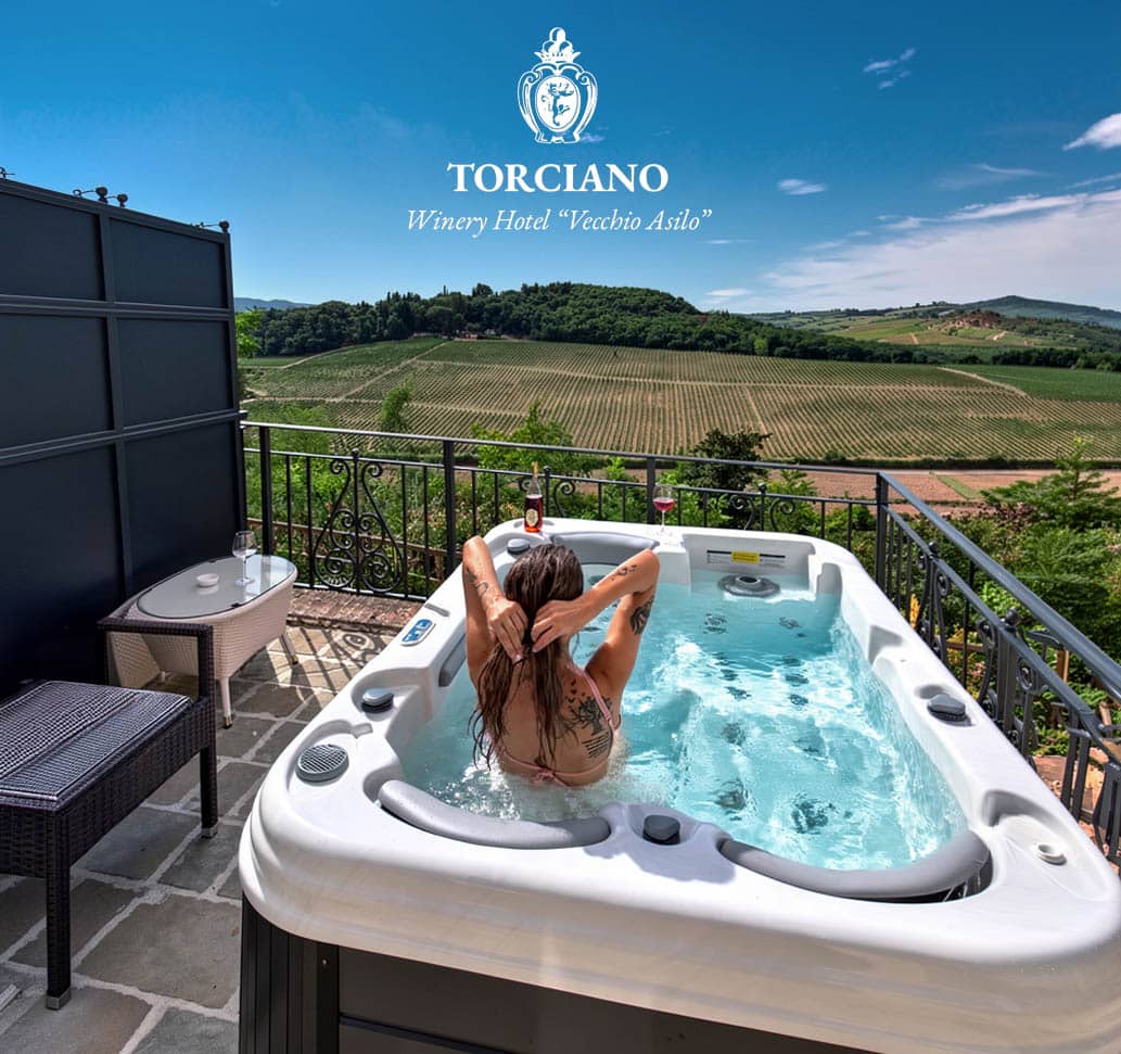 A guest relaxing in the panoramic hot tub overlooking the vineyards at Hotel Torciano Vecchio Asilo