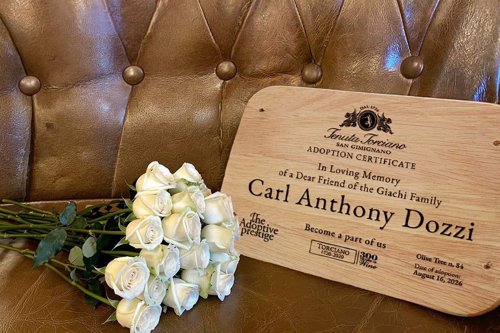 Adoption certificate dedicating Olive Tree n. 84 to Carl Anthony Dozzi, with white roses